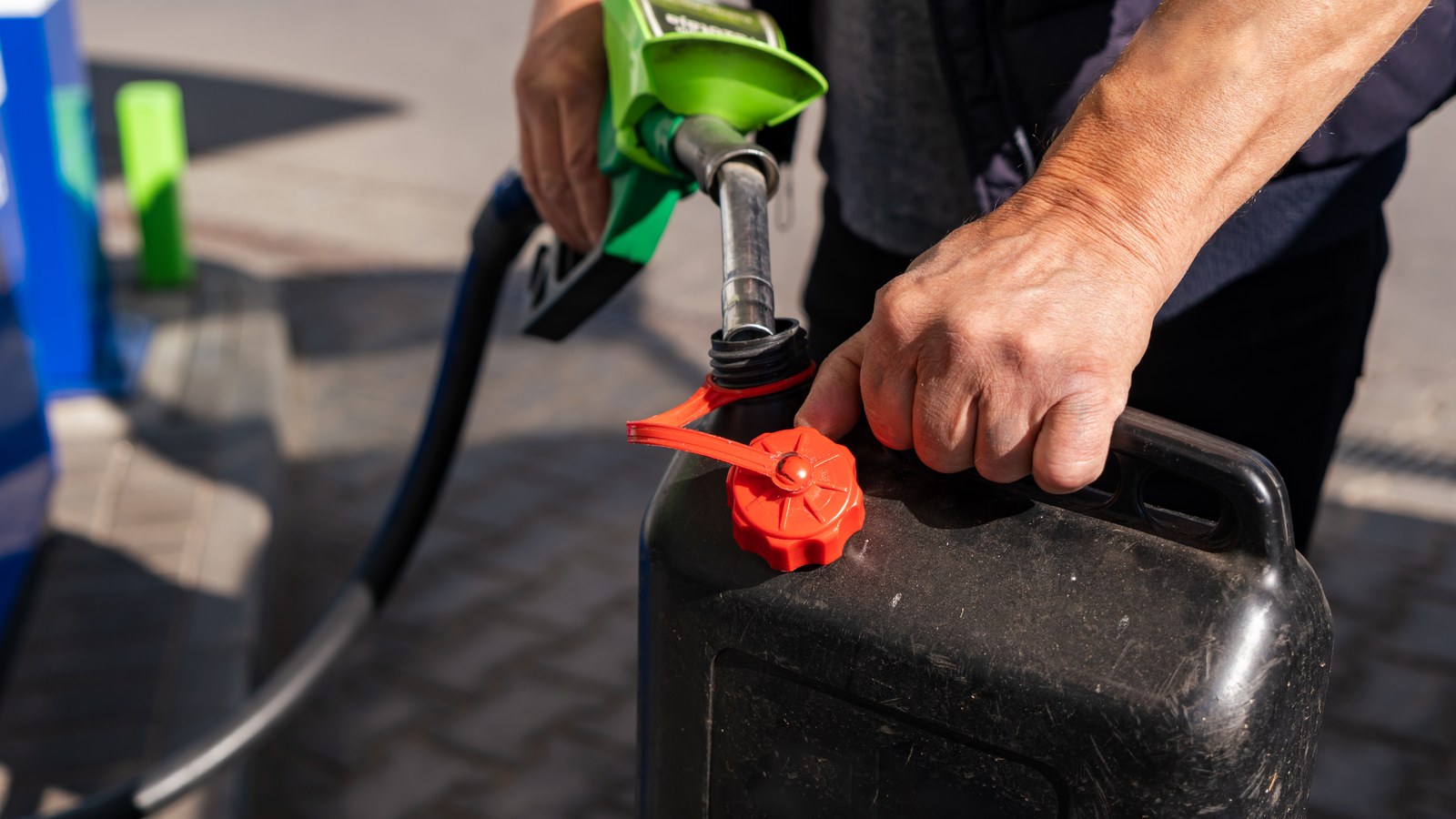 Eine Person befuellt einen Kraftstoffkanister an der Zapfsaeule einer Tankstelle
